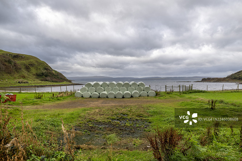 英国苏格兰高地阿德斯利尼什（Ardslignish）水边的乡村风景，有干草堆，天空中布满云彩图片素材