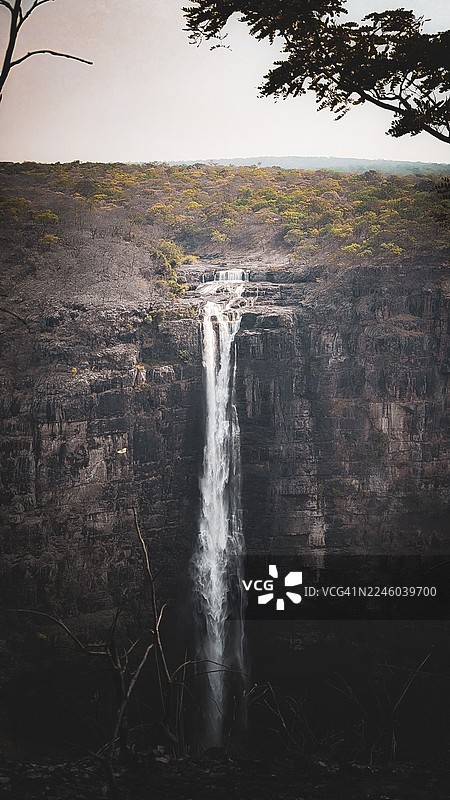 刚果民主共和国卡森加，郁郁葱葱的绿植掩映下，雄伟的瀑布从岩石峭壁上倾泻而下图片素材