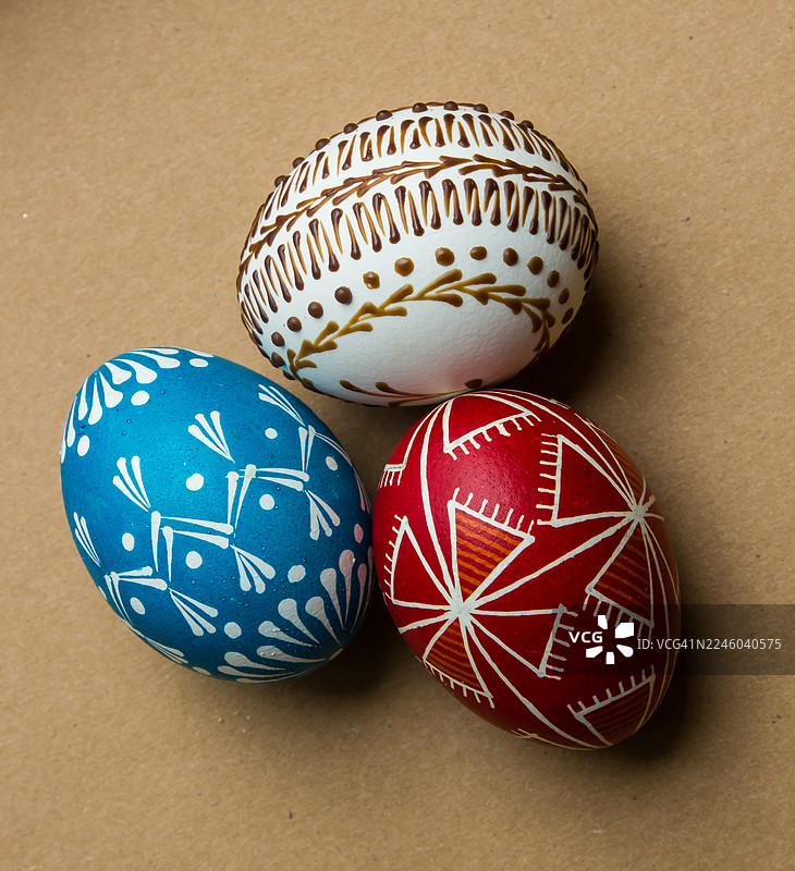 棕色背景上三个装饰精美的复活节彩蛋，展示了传统图案和鲜艳的色彩图片素材