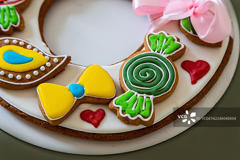 装饰精美的美味姜饼，摆放在白色瓷盘上，带有鲜艳的糖霜图案和粉色丝带点缀图片素材