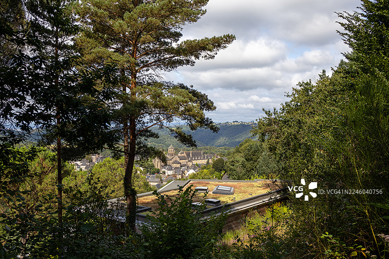 绿意盎然的风景，树木构成了远方历史城镇的框架，天空布满云彩。图片素材