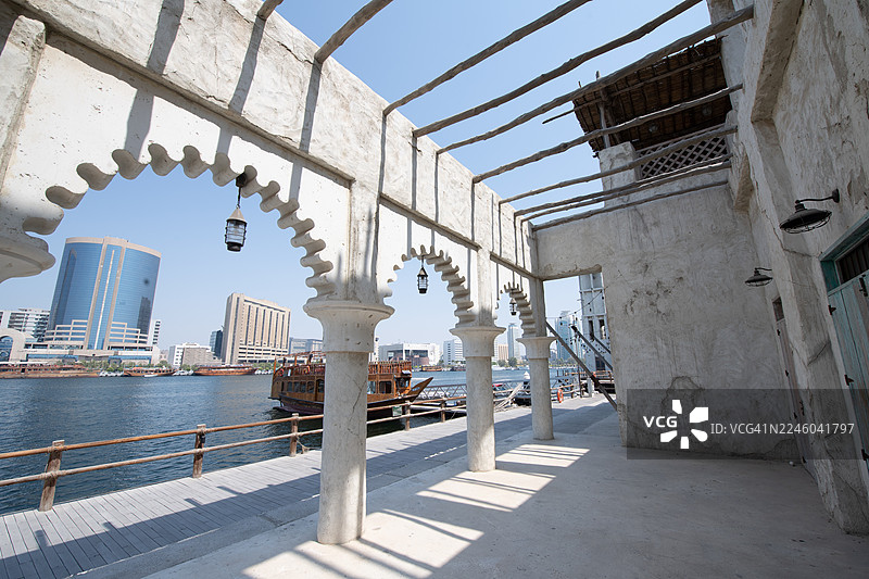 迪拜河畔的历史建筑，背景是现代化的城市天际线，阿拉伯联合酋长国迪拜，布尔迪拜图片素材