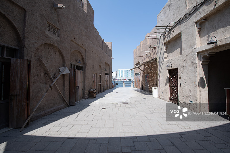 迪拜，阿拉伯联合酋长国，老城区，通往现代城市景观和水景的空旷小巷，具有传统建筑风格图片素材