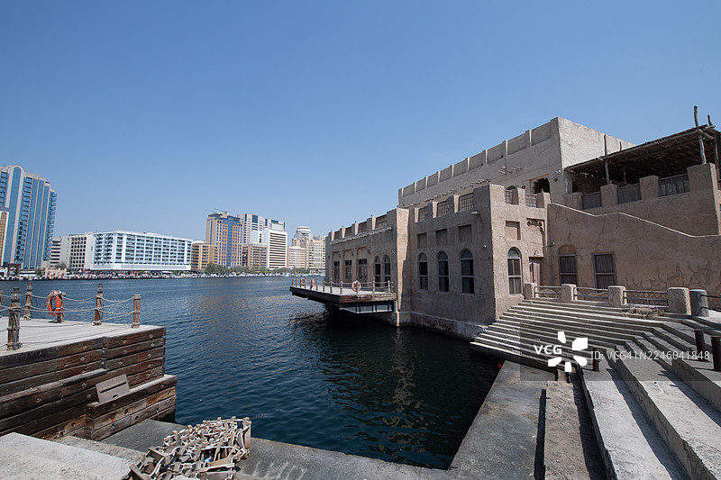 迪拜河畔，历史与现代建筑林立，天空湛蓝，这里是阿拉伯联合酋长国迪拜的布尔迪拜区。图片素材