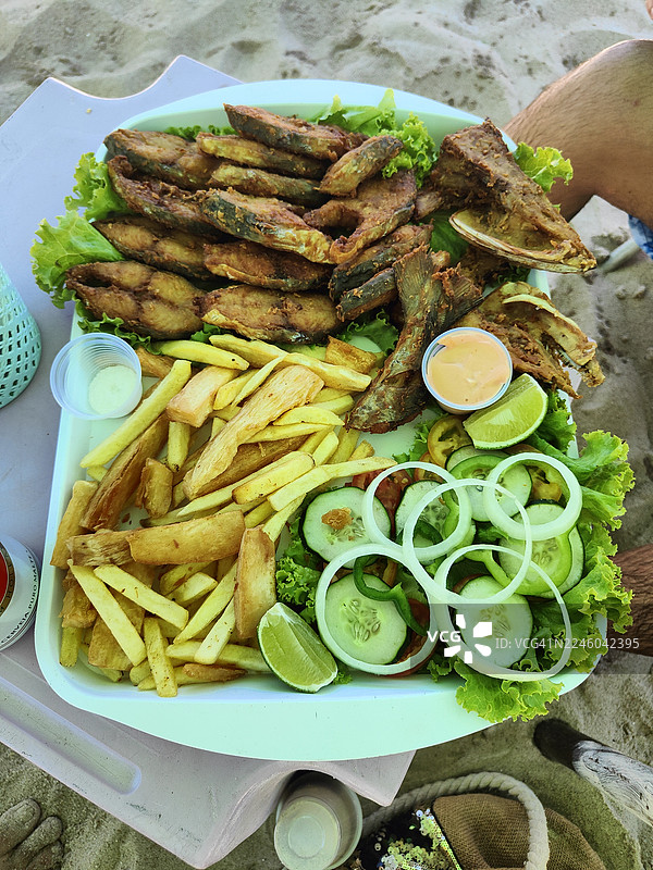 沙滩桌上炸鱼、薯条和沙拉的俯视拼盘图片素材