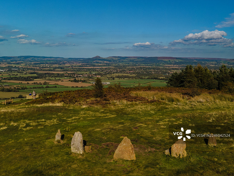 俯瞰广阔绿色山谷的蓝天下的绿色山丘上的古代石圈高角度视图，英国米德尔斯堡，英国，洛德斯通乡村公园图片素材