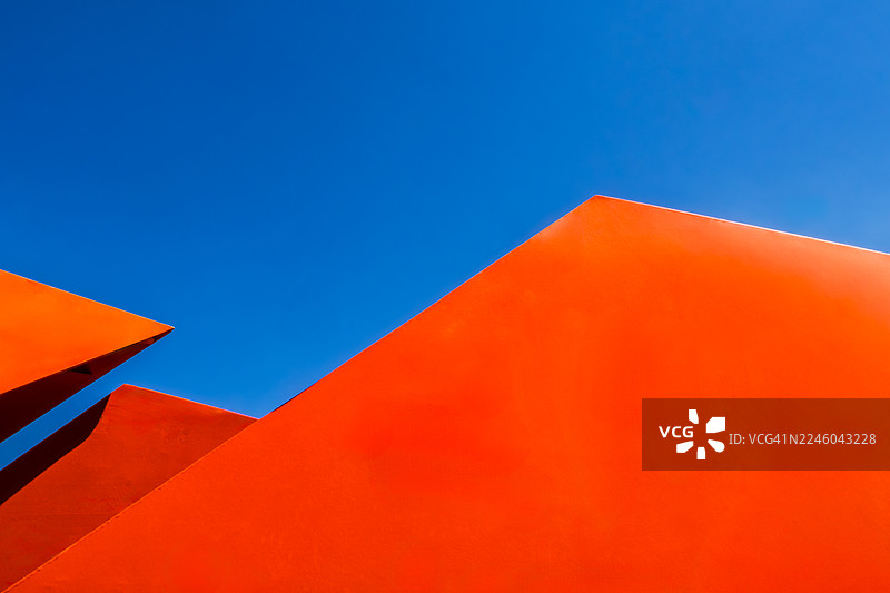 从低角度拍摄的醒目橙色建筑元素，背景是湛蓝的天空，构成一幅现代抽象构图，美国圣路易斯图片素材
