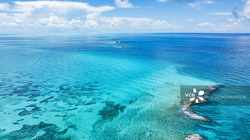 壮丽的空中视角，展示了生机勃勃的绿松石色海水、散落的云朵和湛蓝的天空，突显了大海的美丽图片素材