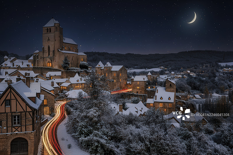 夜幕下的中世纪村庄航拍图，坐落于白雪覆盖的山谷中，月牙形月亮和繁星点点的天空，法国卡奥尔图片素材