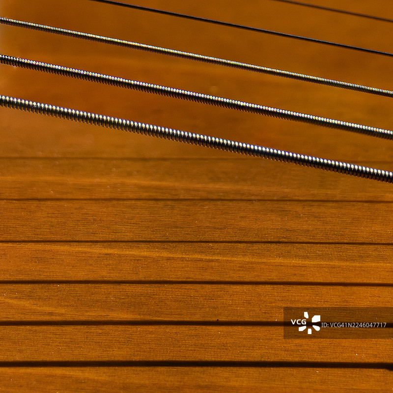 吉他琴弦的特写，覆盖在木质吉他琴身上，突显音乐的质感和精湛工艺图片素材
