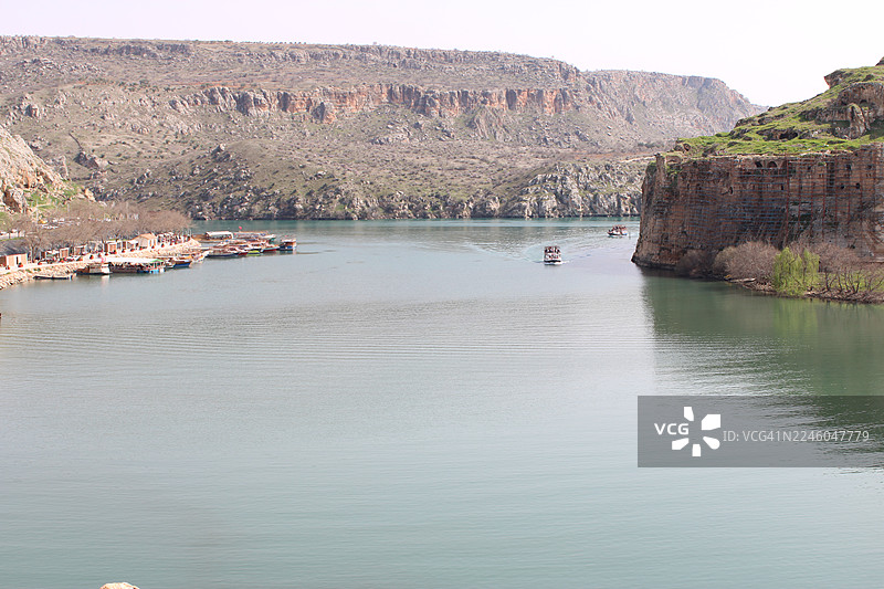 晴朗天空下，河上有船只，背景是岩石山脉的风景图片素材