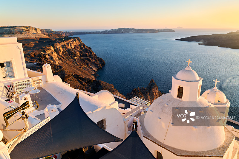 圣托里尼，希腊，日落时分，俯瞰爱琴海和火山悬崖的标志性白色建筑和教堂圆顶的高角度视图图片素材