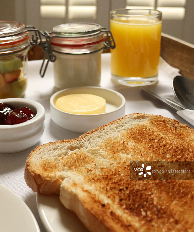 白色桌布上摆放着美味健康的早餐，包括吐司、果酱、水果和橙汁图片素材