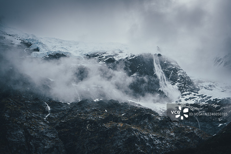 新西兰瓦纳卡罗布罗伊冰川的雾气缭绕的瀑布和雪峰图片素材