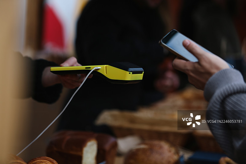 销售人员手持黄色刷卡机和顾客用手机付款图片素材