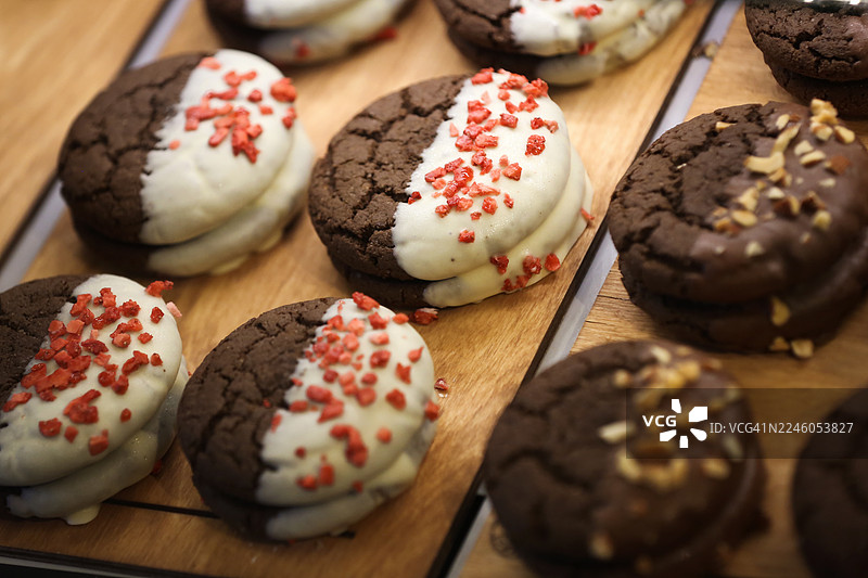 当地咖啡馆的橱窗，展示着带有白巧克力糖霜和冻干覆盆子碎的布朗尼饼干。图片素材