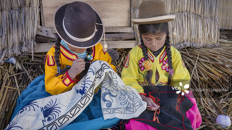 秘鲁乌鲁斯浮岛上的秘鲁年轻女孩们在绣花，的的喀喀湖，秘鲁图片素材
