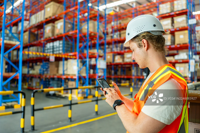 仓库工作人员在大型配送中心使用智能手机检查货架上的货物图片素材