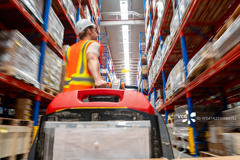 仓库工人驾驶叉车穿过储物架的通道图片素材