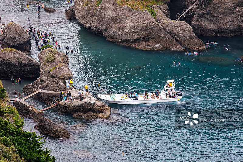 从海角天文台俯瞰的日立海滩美丽的蔚蓝大海。可以看到鬼岛等无人岛、小岛以及当地的岩石海岸。潜水员和浮潜者乘船出海。图片素材