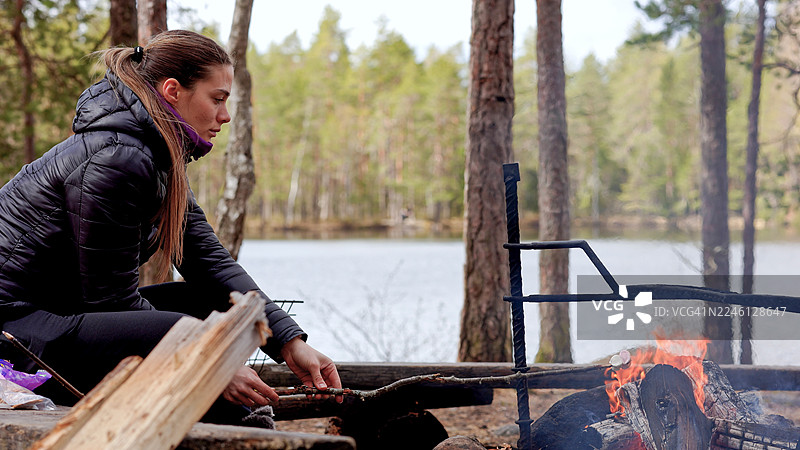 年轻女子在篝火上烤棉花糖图片素材