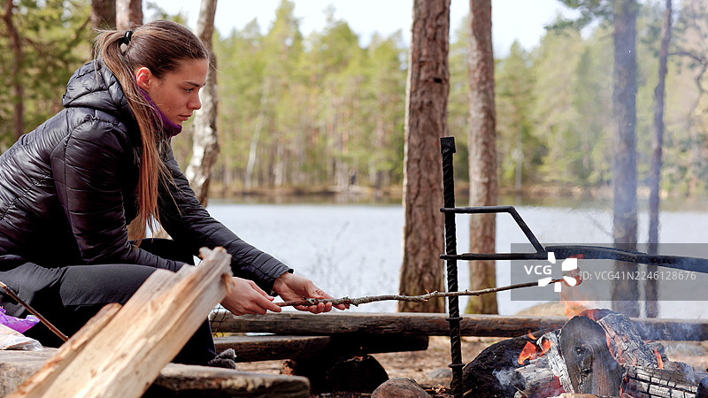 年轻女子在营火上烘烤棉花糖图片素材