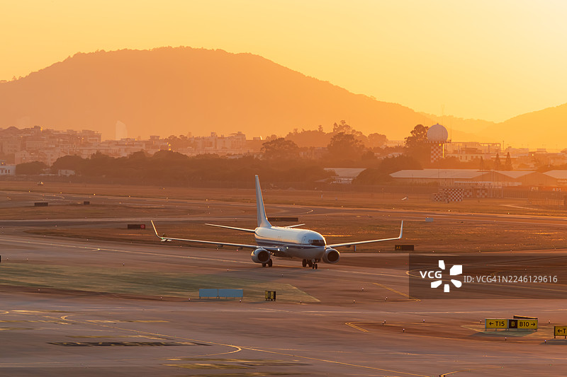 日落时分，客机在机场滑行准备降落图片素材