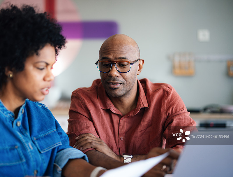 情侣在家中查阅财务文件，使用笔记本电脑和纸质文档图片素材