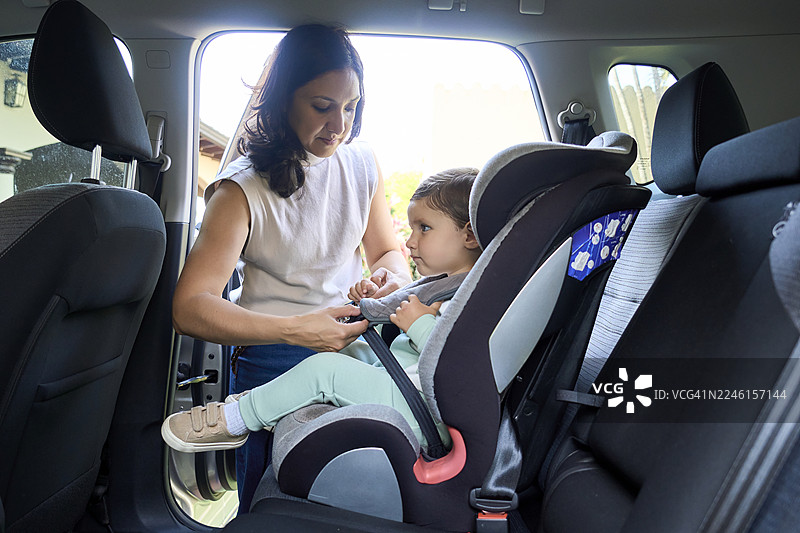 妈妈正在为蹒跚学步的孩子安全地系好汽车座椅图片素材