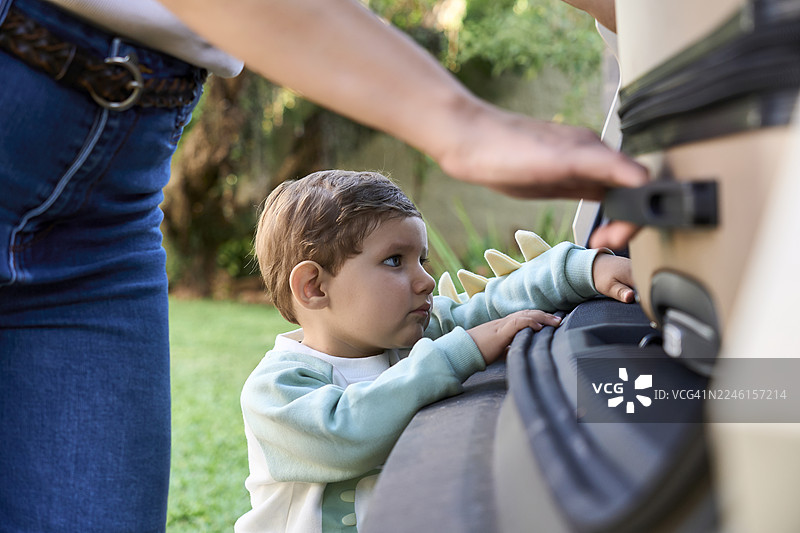 旅行中，蹒跚学步的孩子在父母的陪同下探索汽车后备箱图片素材