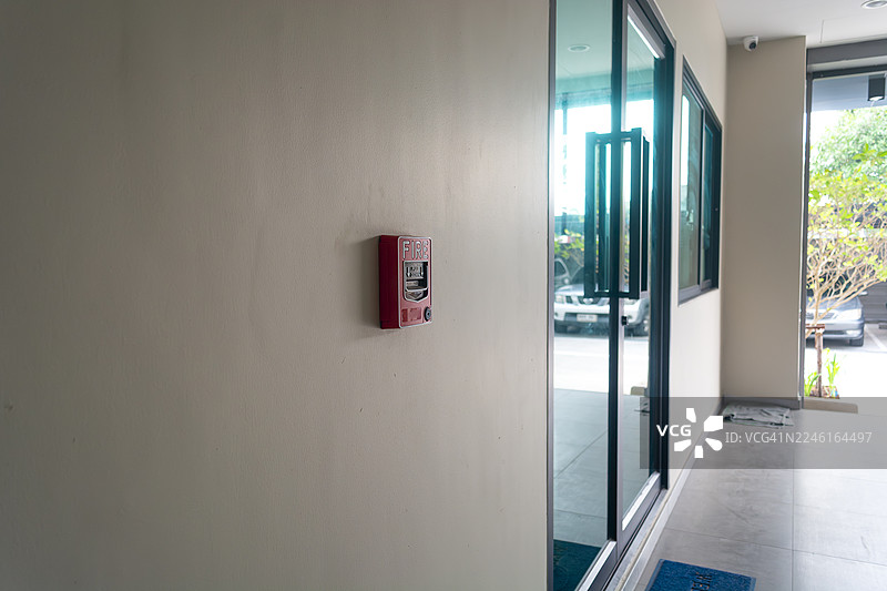 火灾报警开关，一只手正在门旁墙壁上拉动火灾报警器，火灾报警开关。打碎玻璃并按下按钮以激活。带有手部和方向箭头，手按下火灾按钮。图片素材