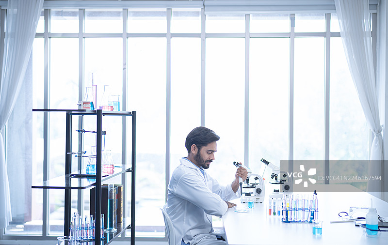 科学家在现代实验室里使用显微镜和试管进行研究，在明亮的空间里推动科学发现和创新。图片素材