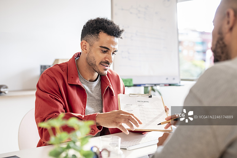年轻的成年男子在现代办公室里向人力资源招聘专员展示简历，进行工作面试图片素材