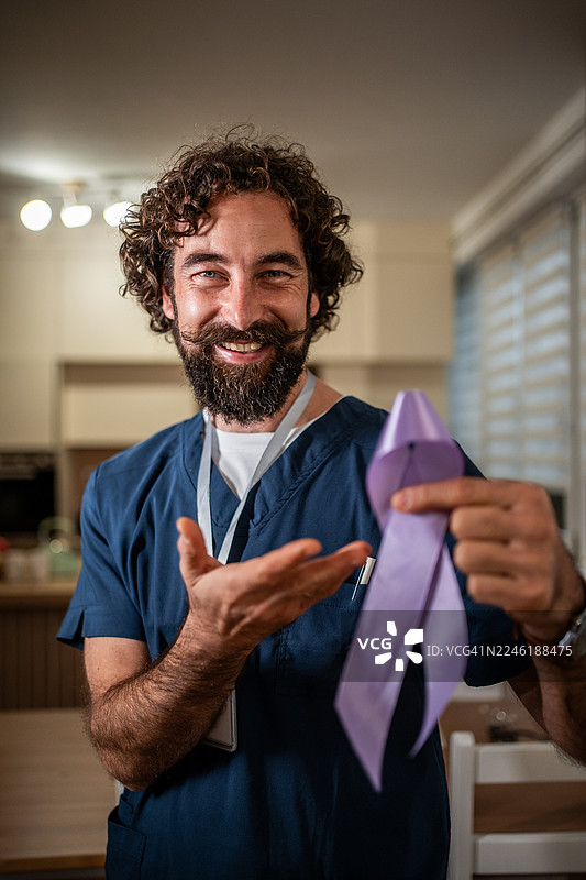 微笑的男医生手持紫色关爱丝带图片素材