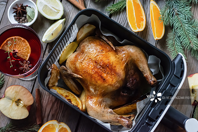 感恩节和圣诞节的节日餐桌上烤鸡或烤火鸡配水果、红酒和香料。图片素材