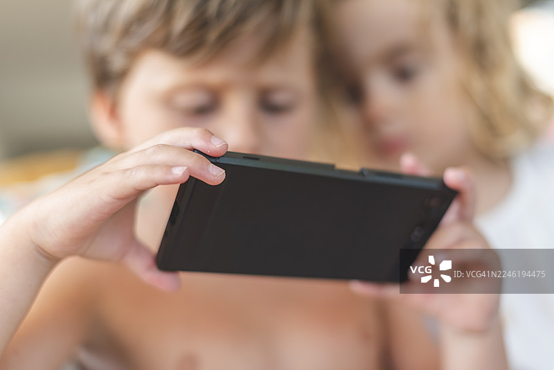 两个兄弟正在用智能手机观看内容图片素材