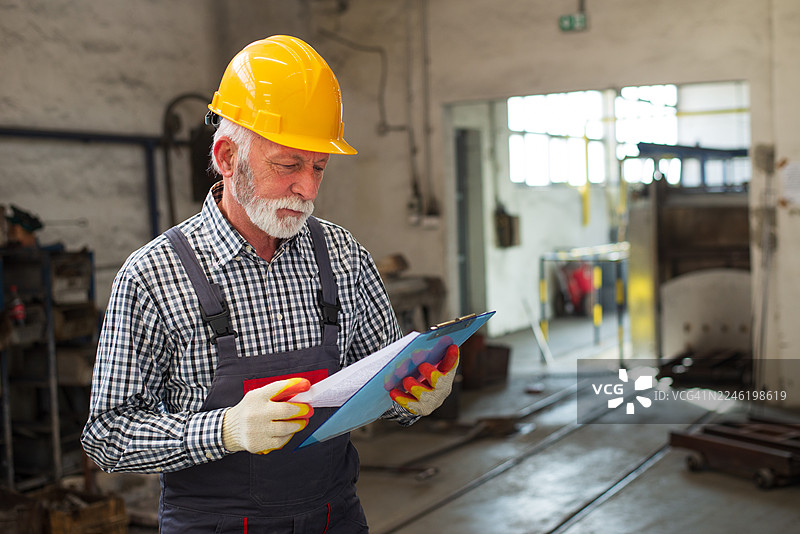 穿着安全帽和工装的资深工程师在工厂工作图片素材