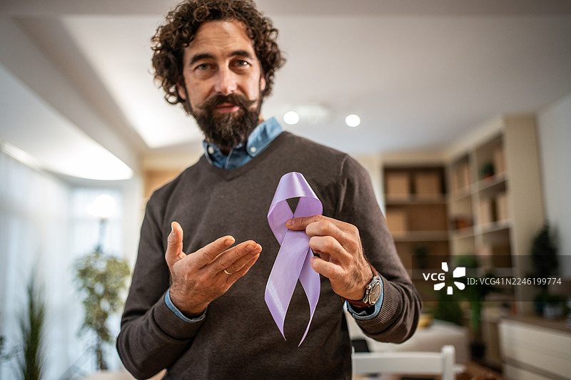 一名男子手持紫色关爱丝带，以示对慈善事业的支持图片素材