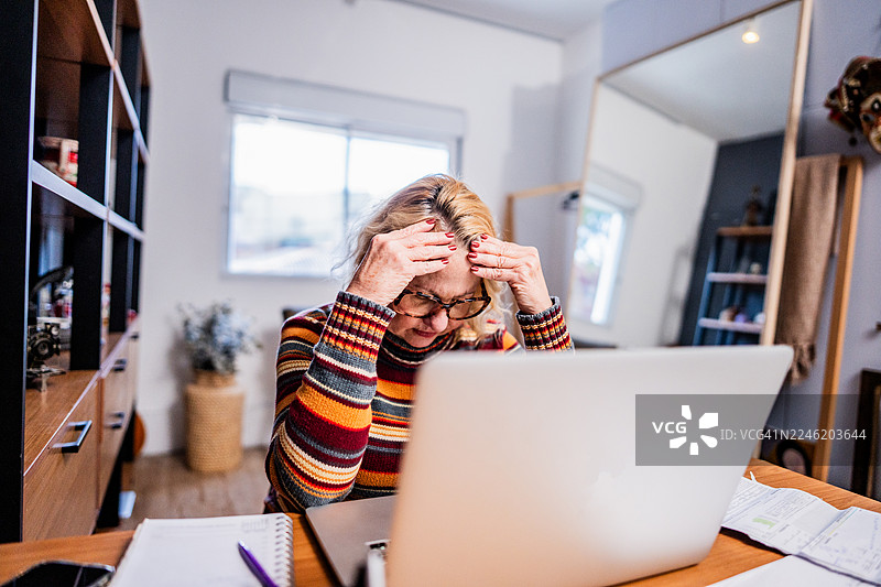 一位年长的女性在家分析财务文件图片素材