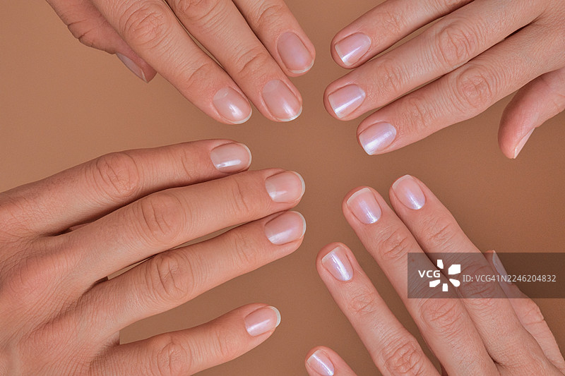 女性的手展示着自然且带有珠光的甲油图片素材