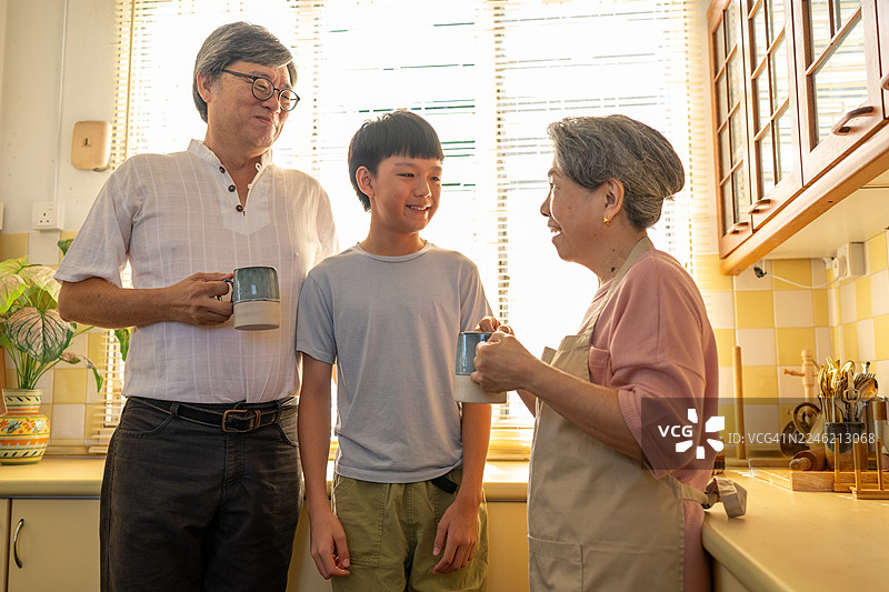 早晨的咖啡与孙子聊天：亚洲家庭厨房的温馨时刻图片素材