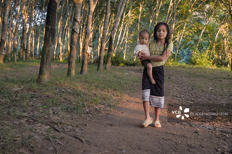 老挝北部偏远村庄里，老挝小女孩抱着一个婴儿图片素材