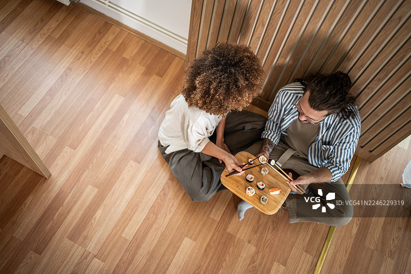 情侣在家里的休闲约会中，在地板上分享寿司图片素材