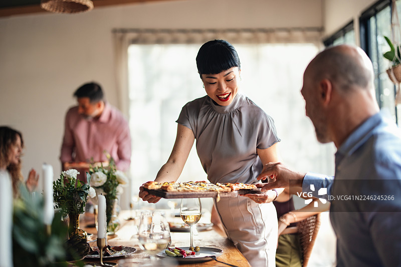 在明亮的晚宴上，朋友们一起享用披萨，分享美食和喜悦。图片素材