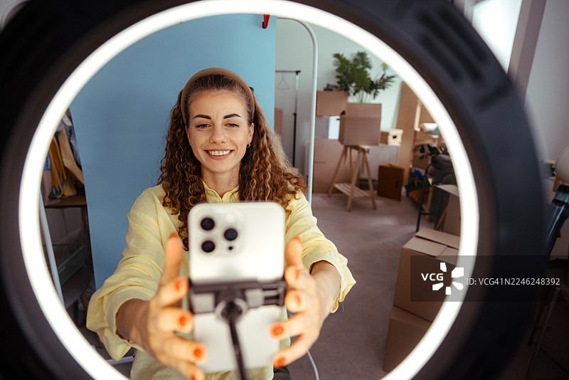 女子在家中使用智能手机和环形灯进行视频博客图片素材