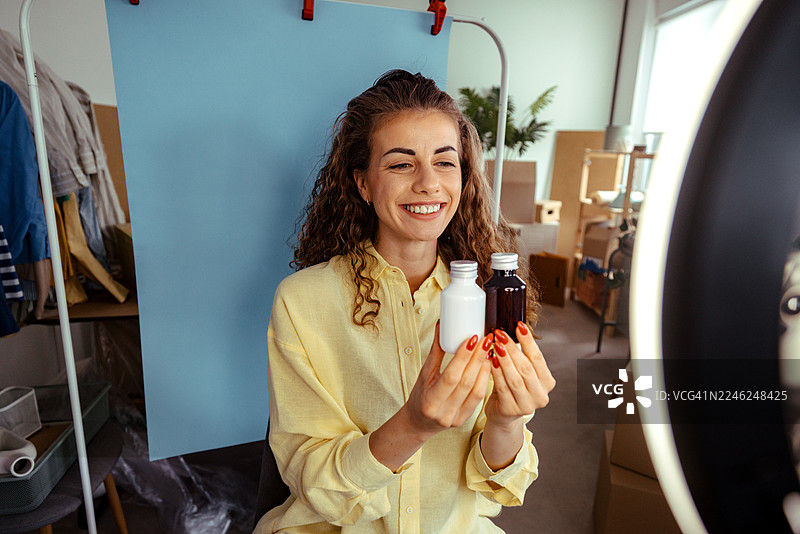 女子在家用智能手机和环形灯拍摄美妆产品视频图片素材