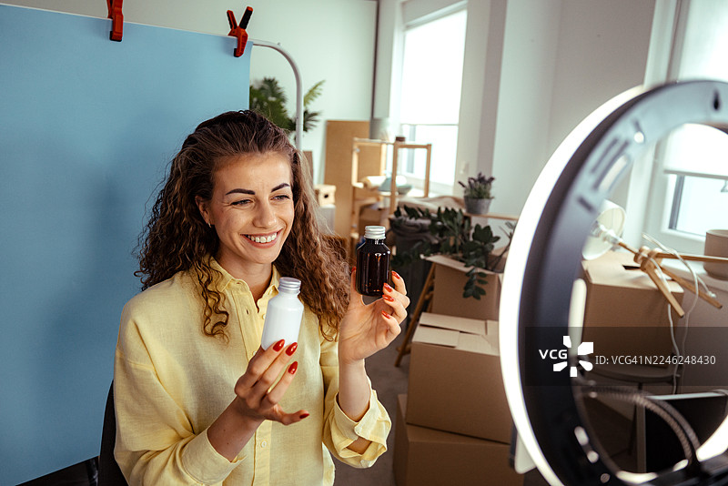 女子在家用智能手机和环形灯拍摄美妆产品视频图片素材