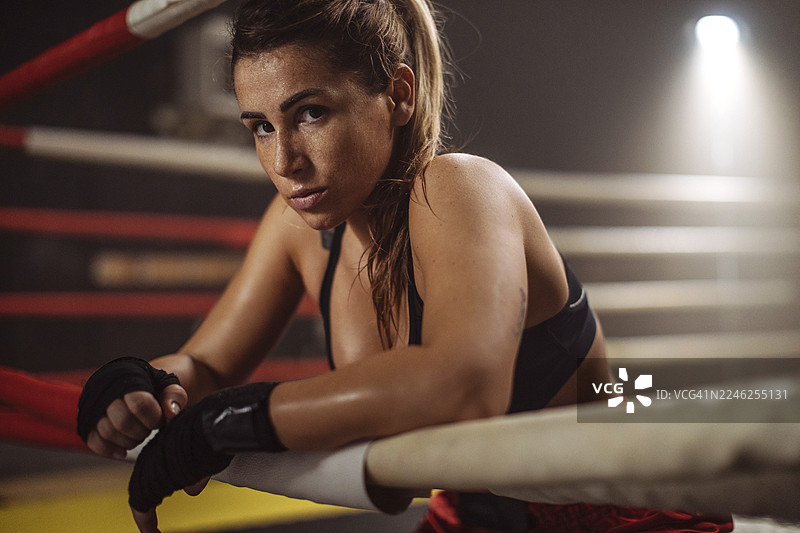训练结束后，女拳击手靠在拳击台绳边休息，展现出强烈的斗志。图片素材