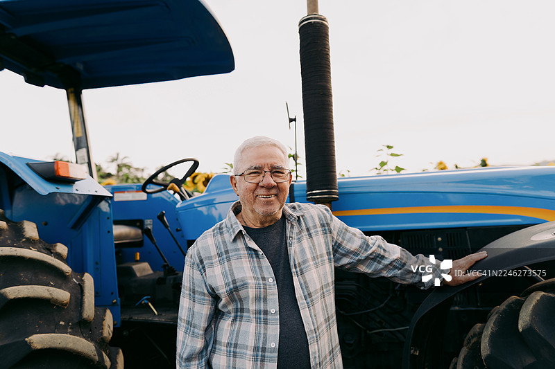 农民站在田地里的拖拉机旁图片素材
