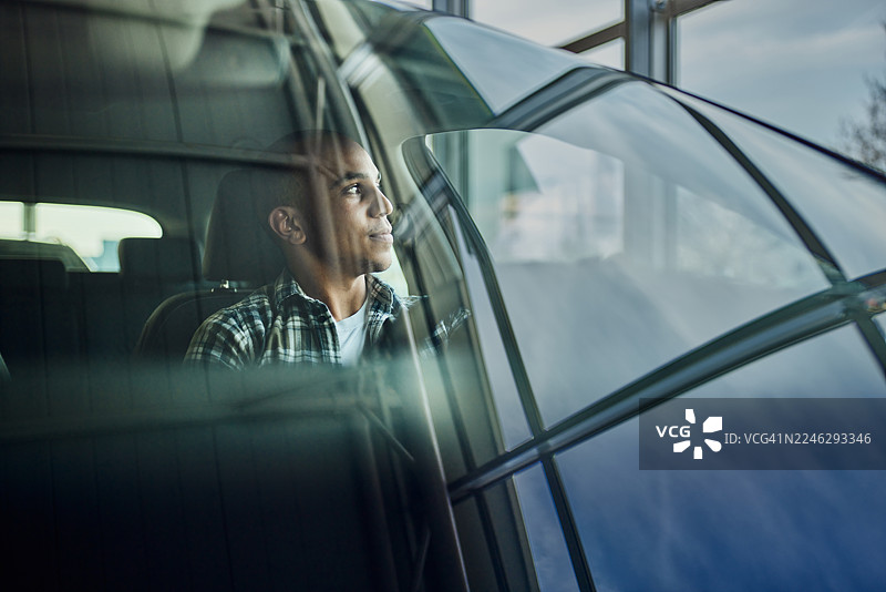 展厅里，一名年轻男子坐在汽车内。图片素材
